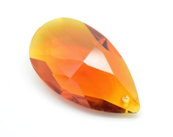 May include: A teardrop-shaped crystal pendant with a faceted design. The pendant is a mix of orange and yellow.