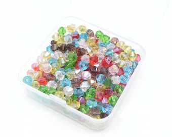 May include: A clear plastic container filled with colorful faceted glass beads. The beads are in various shades of red, green, blue, yellow, and clear.