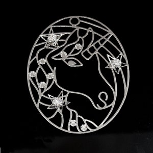 May include: Silver unicorn ornament with rhinestones. The unicorn is outlined in silver and has a detailed design. The ornament is perfect for adding a touch of sparkle to any Christmas tree.
