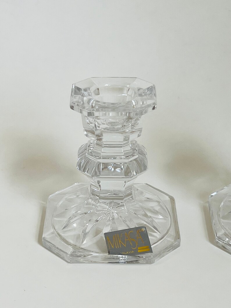 May include: A pair of clear glass candle holders with a cut glass design. The holders are labeled "Mikasa" and "Slovakia".