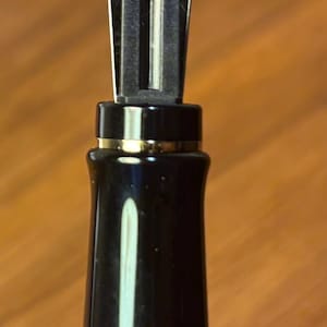 Pu&ograve; includere: Una tazza di ceramica bianca con manico nero e la scritta "But First, Coffee" in nero, in grassetto. La tazza &egrave; su una superficie bianca.