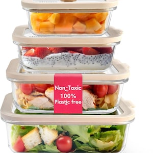 May include: A stack of four rectangular glass food storage containers with beige lids. The containers are filled with various foods, including chopped fruit, strawberries with a white substance, chicken and pasta, and a salad. A pink label reads "Non-Toxic 100% Plastic free."