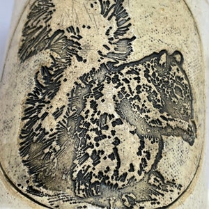May include: A ceramic mug with a detailed black and white image of a squirrel on the front. The mug has a light beige background.