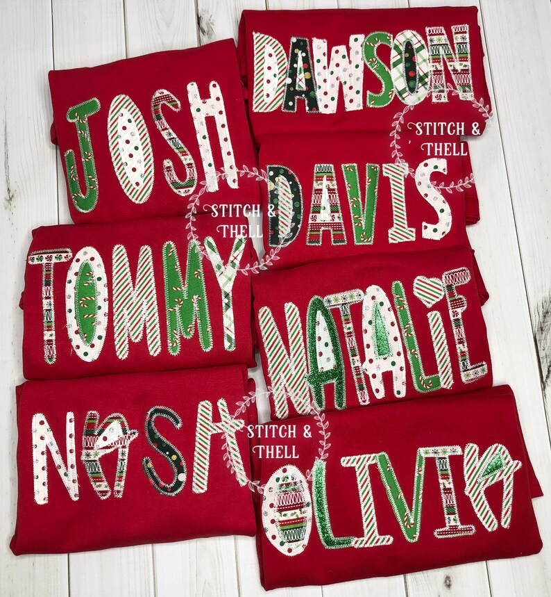 May include: Six red t-shirts with different names on them, each name is made of different Christmas-themed fabric scraps. The names are Josh, Dawson, Davis, Tommy, Natalie, and Olivia.