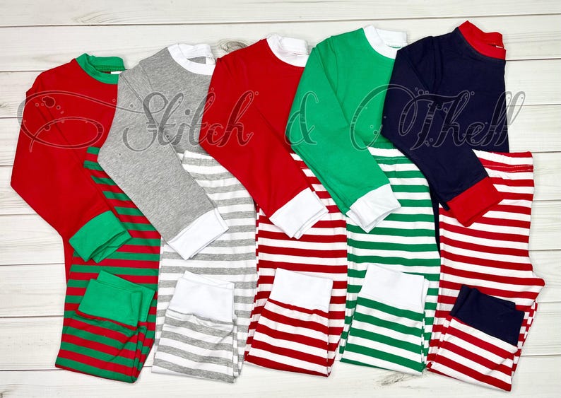 May include: Five pairs of striped pajamas in red, green, gray, and navy blue with white stripes. The pajamas have long sleeves and a crew neck.