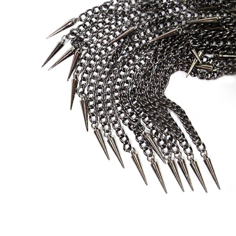 May include: A black metal chain necklace with multiple rows of chains and sharp, pointed spikes hanging from the bottom.