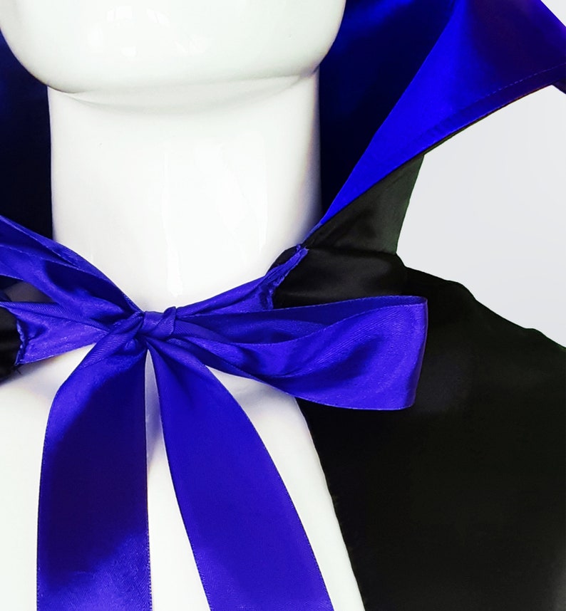 May include: A black satin cape with a blue satin lining and a blue satin ribbon tied in a bow at the neck.