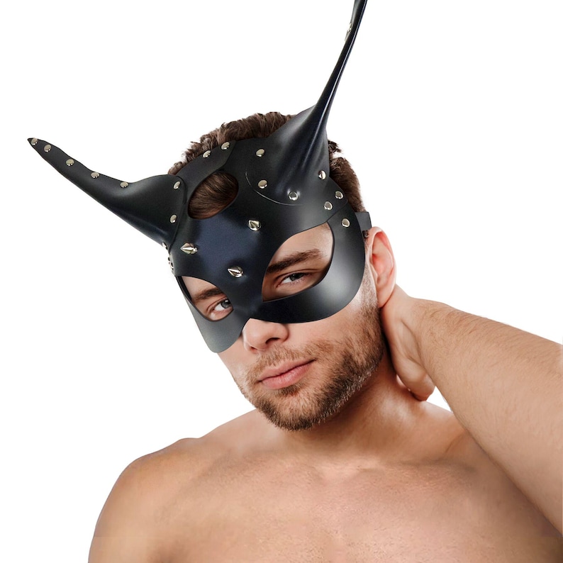 Puede incluir: Una m&aacute;scara de cuero negro con un dise&ntilde;o puntiagudo en forma de oreja y tachuelas plateadas. La m&aacute;scara tiene agujeros para los ojos y una peque&ntilde;a abertura para la nariz.
