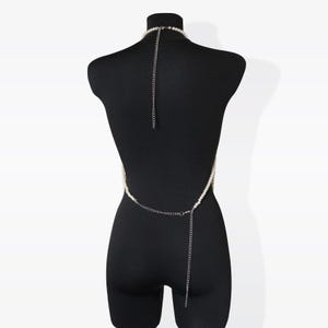 K&ouml;nnte beinhalten: Eine wei&szlig;e Perlen-K&ouml;rperkette mit einer silbernen Kette. Die Kette wird auf einem schwarzen Mannequin getragen.