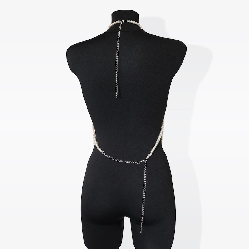 K&ouml;nnte beinhalten: Eine wei&szlig;e Perlen-K&ouml;rperkette mit einer silbernen Kette. Die Kette wird auf einem schwarzen Mannequin getragen.