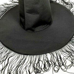 May include: A black witch hat with a wide brim and a tall crown. The brim is trimmed with black fringe.