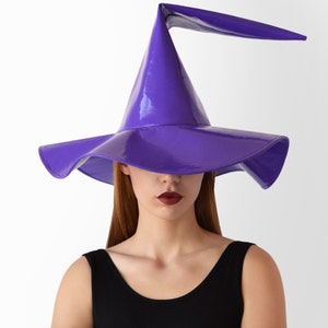 May include: A purple witch hat with a wide brim and a tall, pointed crown. The hat has a shiny, glossy finish.
