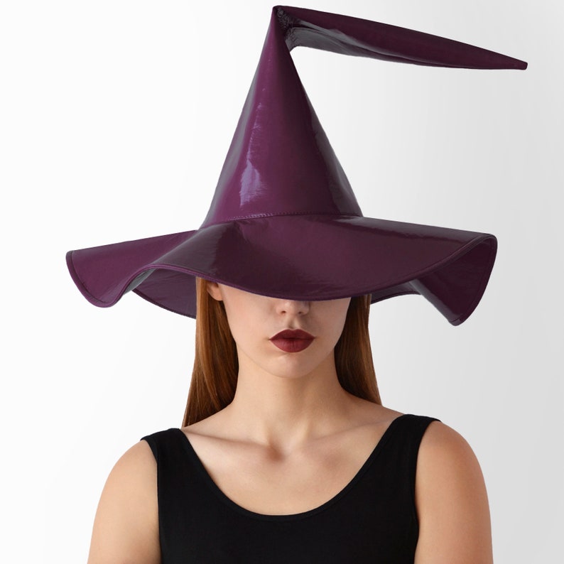 May include: A purple witch hat with a tall, pointed crown and a wide brim. The hat has a glossy finish and a curved brim.