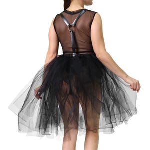 May include: Black tulle skirt with a sheer top and leather harness. The skirt is layered and flared, creating a voluminous effect. The top is sleeveless and see-through, with a harness detail.