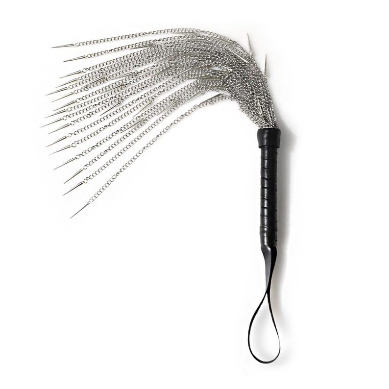 May include: A black leather-wrapped handle with a silver chain whip attached. The whip has multiple strands of chain with pointed ends.