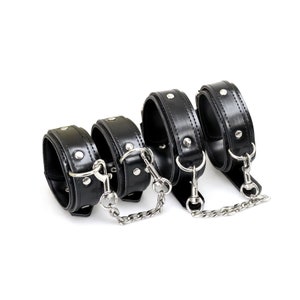 May include: Four black leather wrist cuffs with silver metal accents and connecting chains.