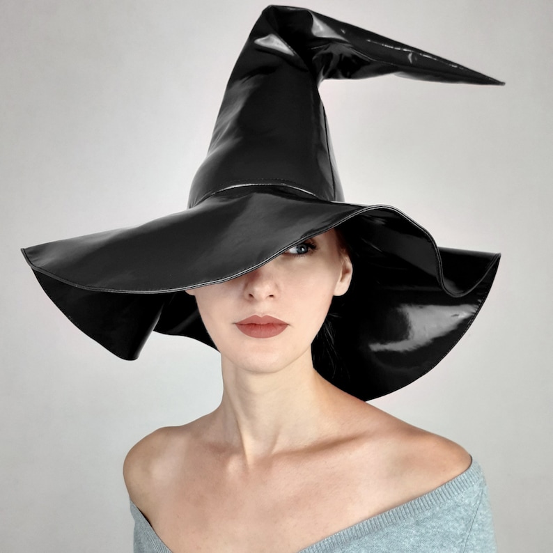 May include: A black witch hat with a wide brim and a tall, pointed crown. The hat is made of a shiny, patent leather material.