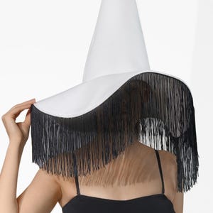 May include: A white witch hat with a wide brim and black fringe trim.