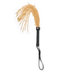 May include: A black leather-wrapped whip with a gold chain tassel and multiple gold spikes.