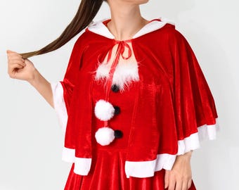 May include: A red velvet Santa Claus dress with white trim and a matching cape. The dress has a white fur trim around the neckline and a white fur pom-pom on the front.