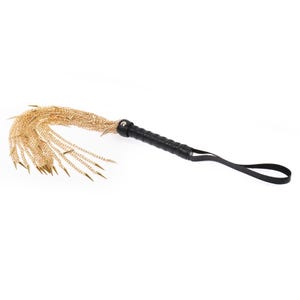 May include: A black leather-wrapped handle with a gold chain whip. The whip has multiple strands of chain with sharp metal tips.