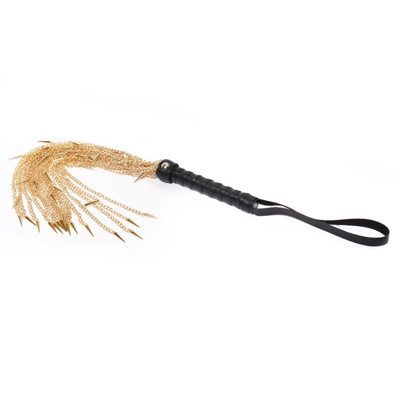 May include: A black leather-wrapped handle with a gold chain whip. The whip has multiple strands of chain with sharp metal tips.