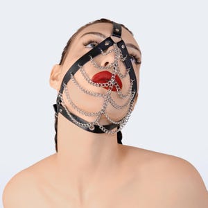 May include: A black leather face mask with a silver chain design. The mask covers the eyes, nose, and mouth.