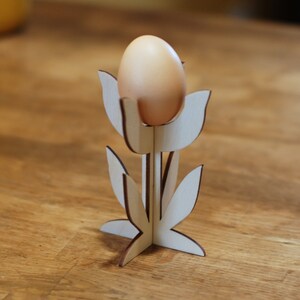Könnte beinhalten: Ein hölzerner Eierhalter in Form einer Tulpe mit einem braunen Ei darin.