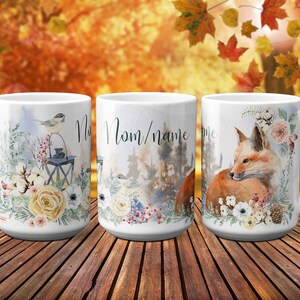 May include: Three white ceramic mugs with different designs. The first mug features a bird perched on a lantern with floral accents. The second mug has a forest scene with the text "Mom/name". The third mug features a fox curled up with floral accents.