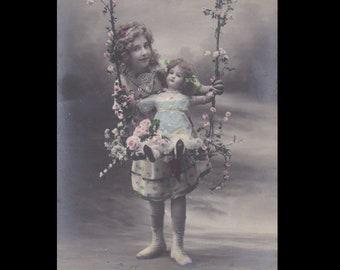 Vintage-Postkarte ∙ Kleines Mädchen mit ihrer Puppe auf einer Schaukel