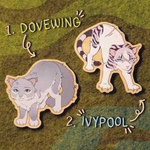 Könnte beinhalten: Zwei hölzerne Katzenfiguren-Ausschnitte, eine graue und eine weiße mit schwarzen Streifen. Die graue Katze heißt Dovewing und die weiße Katze heißt Ivypool.