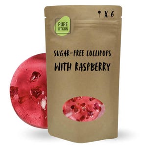 Puede incluir: Una bolsa de papel marrón con seis piruletas sin azúcar con sabor a frambuesa. La bolsa tiene una ventana transparente que muestra los caramelos rojos con trozos de frambuesa. El texto de la bolsa dice "Piruletas sin azúcar con frambuesa" y "Pure Ktchn".