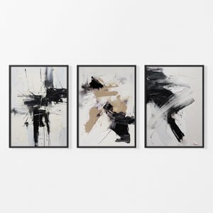 Puede incluir: Tres pinturas abstractas en marcos negros. Las pinturas son en tonos de blanco, negro y beige. Las pinturas son todas de diferentes tamaños y formas.