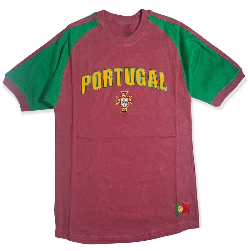 May include: A maroon t-shirt with green sleeves and a yellow "PORTUGAL" graphic. The shirt features the Portuguese coat of arms and a small Portuguese flag patch.
