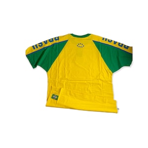 May include: Yellow and green t-shirt with blue "BRASIL" text and stars on the back. The shirt has green sleeves with blue "BRASIL" text on the sleeves.