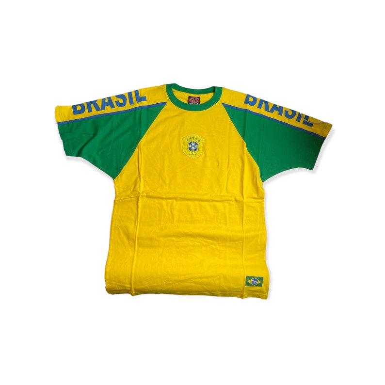 May include: Yellow, green, and blue short-sleeved t-shirt with the word "BRASIL" on the sleeves and a small Brazilian flag patch on the front.