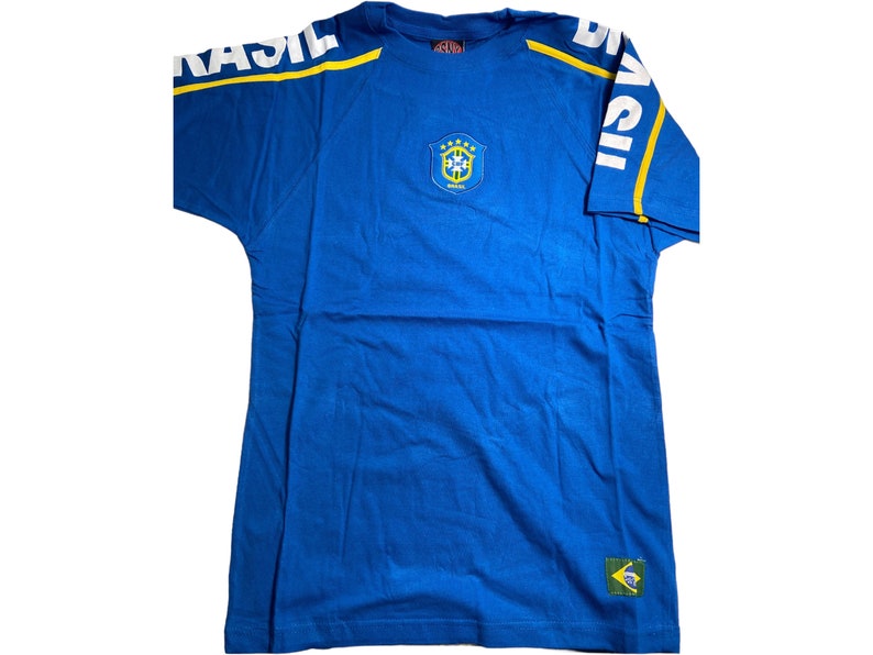 May include: Blue t-shirt with a yellow and white "BRASIL" graphic on the sleeve and a yellow and green crest with "BRASIL" text on the front.