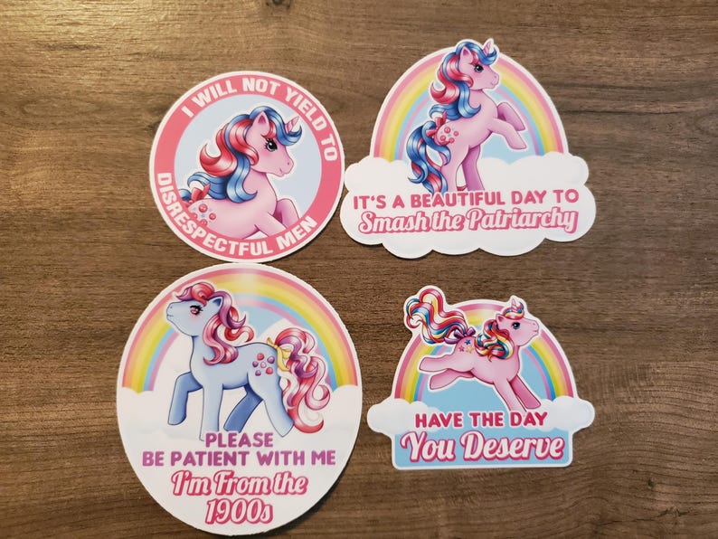 May include: Four vinyl stickers featuring cartoon ponies with rainbow backgrounds. One circular sticker reads I WILL NOT YIELD TO DISRESPECTFUL MEN. Another reads IT'S A BEAUTIFUL DAY TO Smash the Patriarchy. A third says PLEASE BE PATIENT WITH ME I'm From the 1900s. The last reads HAVE THE DAY You Deserve.