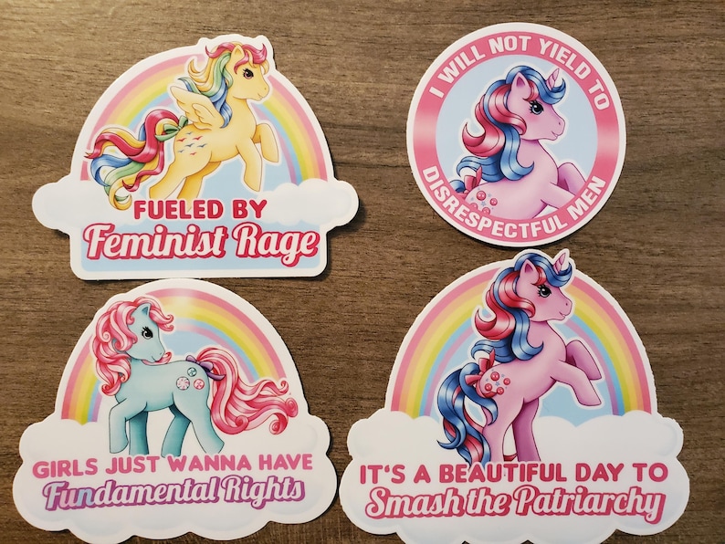 May include: Four vinyl stickers featuring cartoon ponies with rainbow motifs and text. One reads FUELED BY Feminist Rage, another I WILL NOT YIELD TO DISRESPECTFUL MEN, the third GIRLS JUST WANNA HAVE Fundamental Rights, and the last IT'S A BEAUTIFUL DAY TO Smash the Patriarchy.