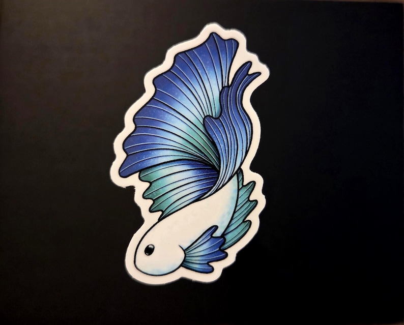 Op de afbeelding: Een sticker met een gestileerde betta-vis, met een wit lichaam en een vloeiende staart. De staart loopt over van blauw naar turquoise, met gedetailleerde lijnen. De sticker heeft een witte rand en staat op een zwarte achtergrond.