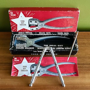 May include: Vintage York Nut Sheller set with a red and black box. The box features the text "The Texan" and "York Nut Sheller". The set includes a nutcracker and a pick, designed for shelling various nuts and cracking lobster claws.
