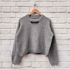 May include: A white ceramic mug with a black handle and the text "But First, Coffee" in a bold, black font. The mug is sitting on a wooden surface. The mug is approximately 4 inches tall.