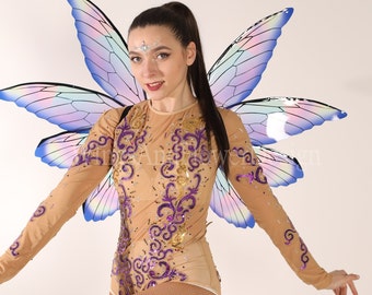 May include: A woman wearing a sparkly, sheer, nude-colored leotard with purple and gold embellishments. She is wearing a pair of iridescent butterfly wings with a purple, blue, and white color scheme.