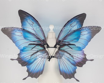 May include: A pair of blue and purple butterfly wings with black veins. The wings are attached to a white mannequin torso.