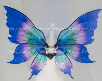 May include: A pair of blue, purple, and green butterfly wings with a black elastic strap for attaching to the back.