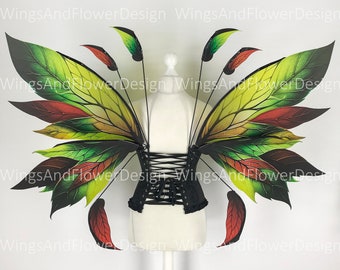May include: A pair of fairy wings with a black corset. The wings feature a leaf design in shades of green, yellow, and red. The corset is black and laced up the front. The wings are attached to the corset with thin black rods.