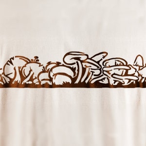 May include: A brown graphic of a cluster of mushrooms on a white t-shirt.