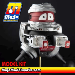 May include: A B.O.B. LF28 robot model kit featuring a silver and red color scheme with white eyes. The figure has two clear plastic cannons extending forward. The Mojo Modelworks logo is visible in the top left, and the text MODEL KIT MojoModelworks.com appears at the bottom.