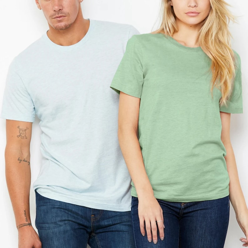 Puede incluir: Dos camisetas lisas, una azul claro y otra verde claro, son usadas por dos personas. Ambas camisetas son de manga corta y cuello redondo.