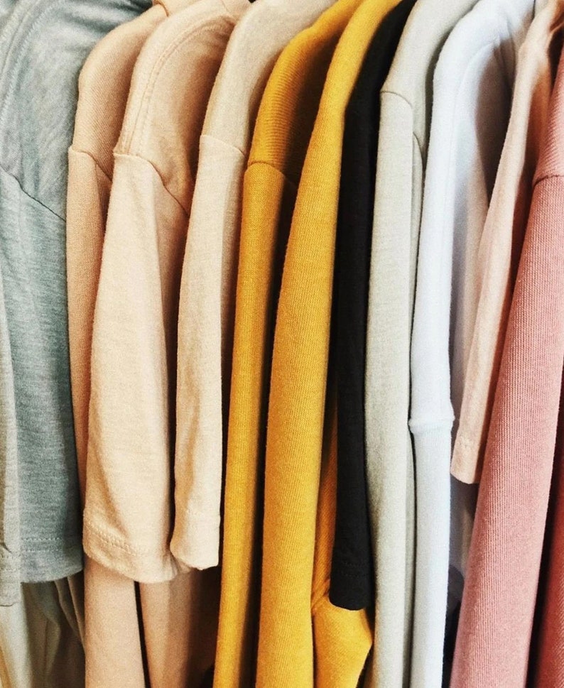 Puede incluir: Una colecci&oacute;n de camisetas dobladas en varios colores, incluyendo azul claro, beige, amarillo y rosa.